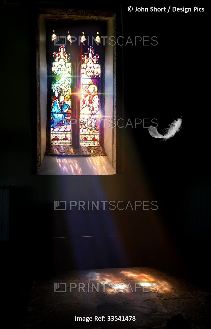 A white feather floats down from the ceiling of a church with sunlight shining ...