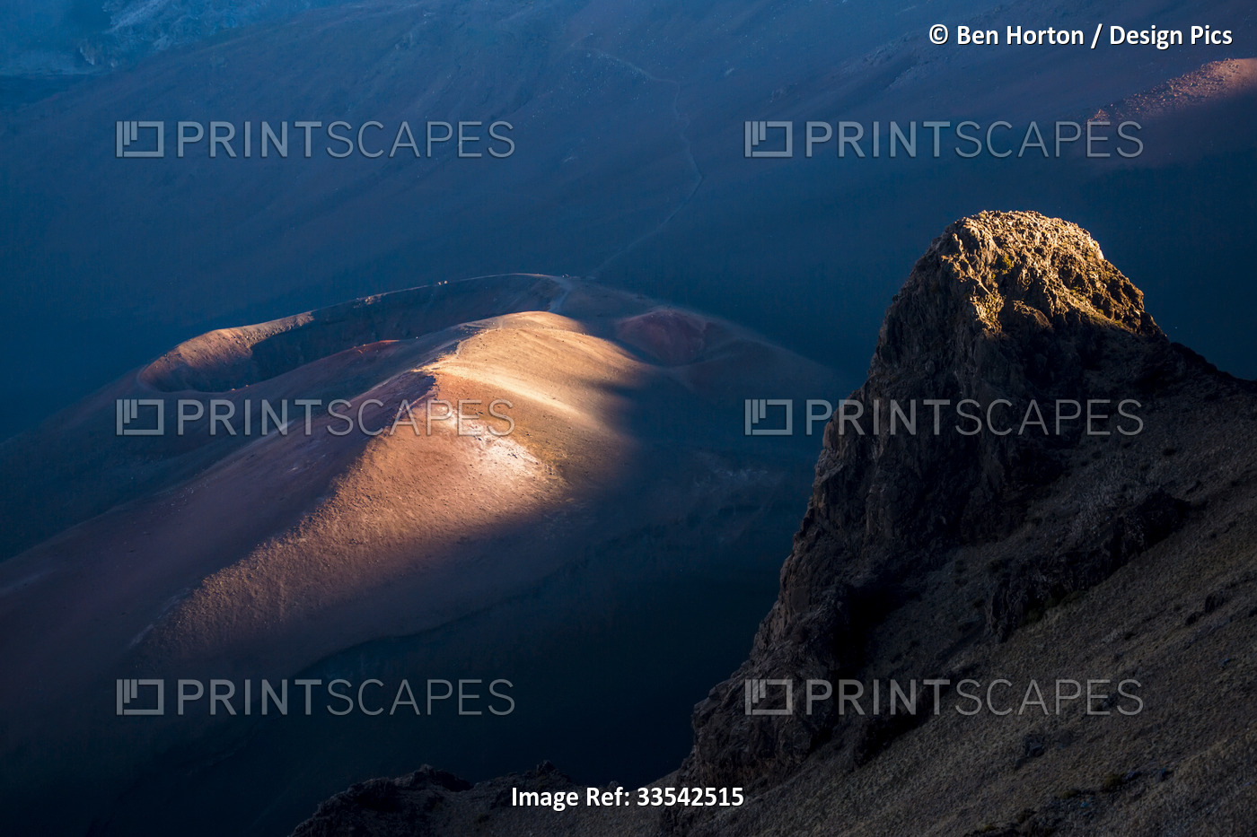 Sunlit tips of a volcanic rock formation and the Haleakala Crater at sunset; ...