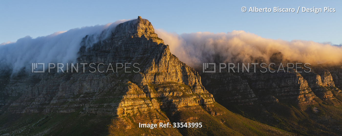 A view of sunlit Table Mountain from Lion's Head with a cloud formation ...