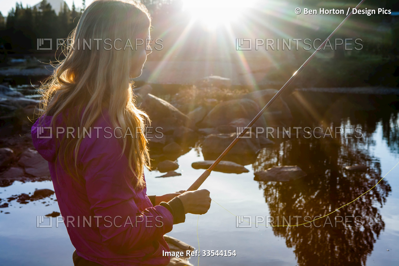 A young woman fly fishing at sunset.