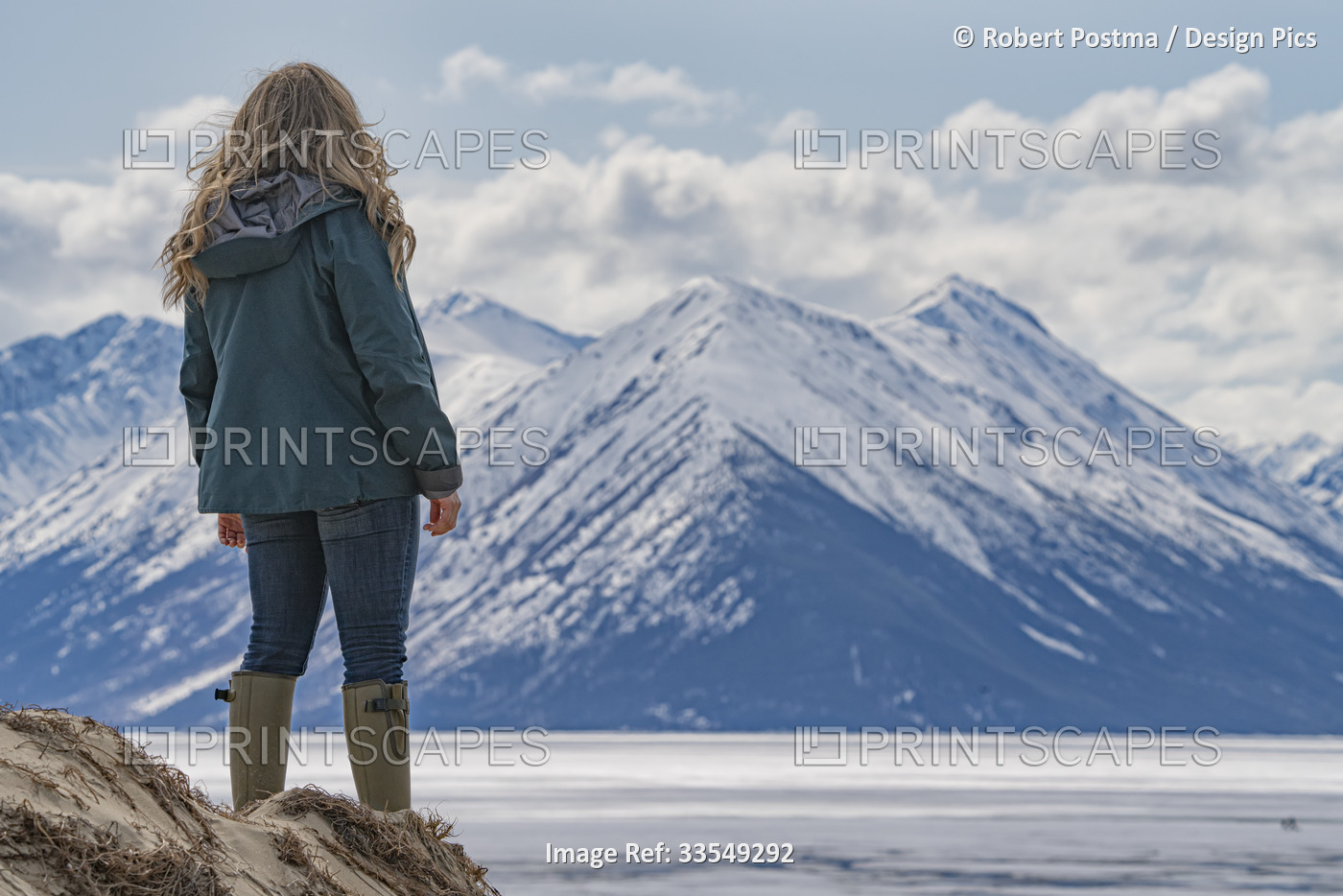 View taken from behind of a woman standing on the sand dunes and looking out ...