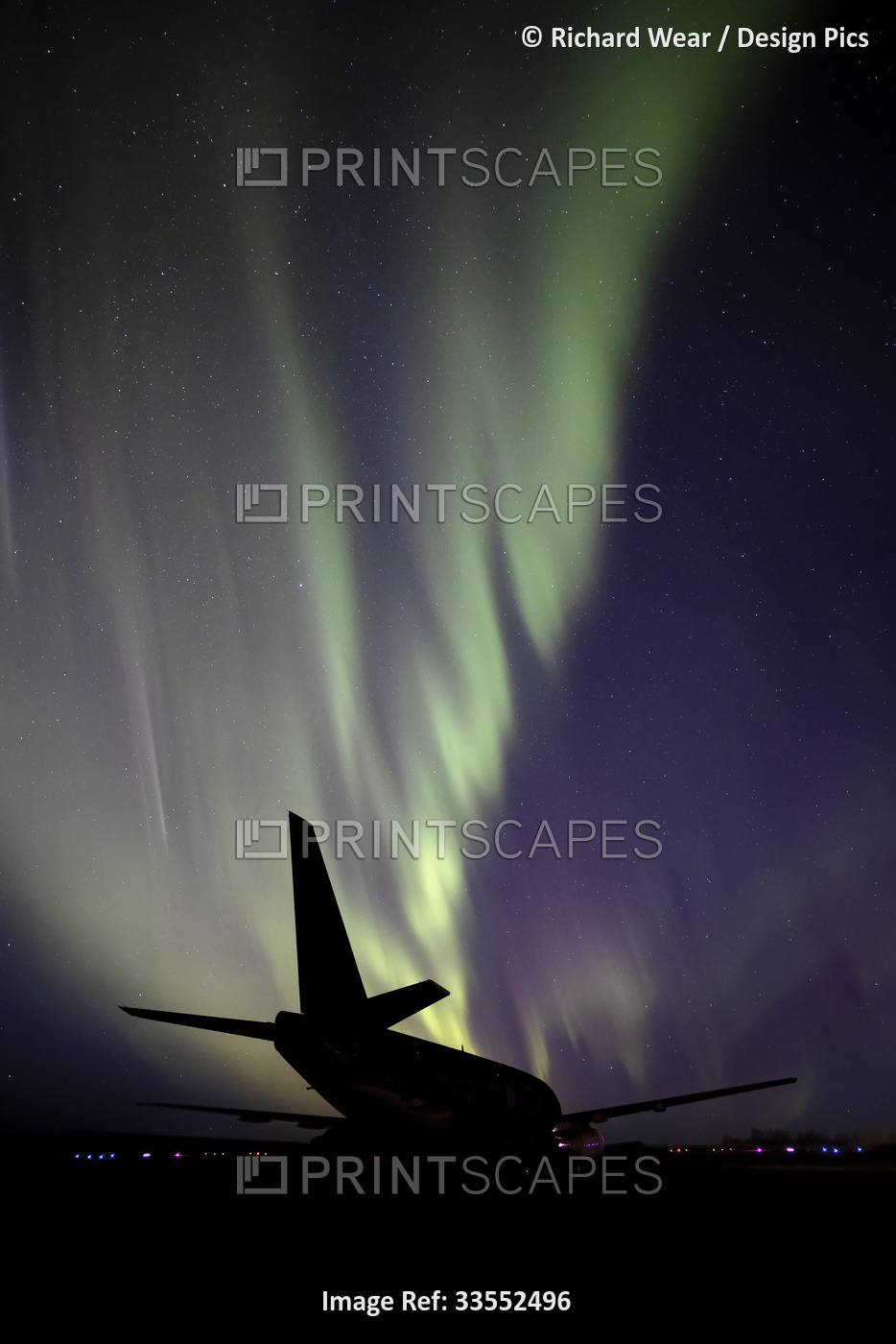 Silhouetted airplane with Aurora Borealis in the starry night sky; Villeneuve, ...