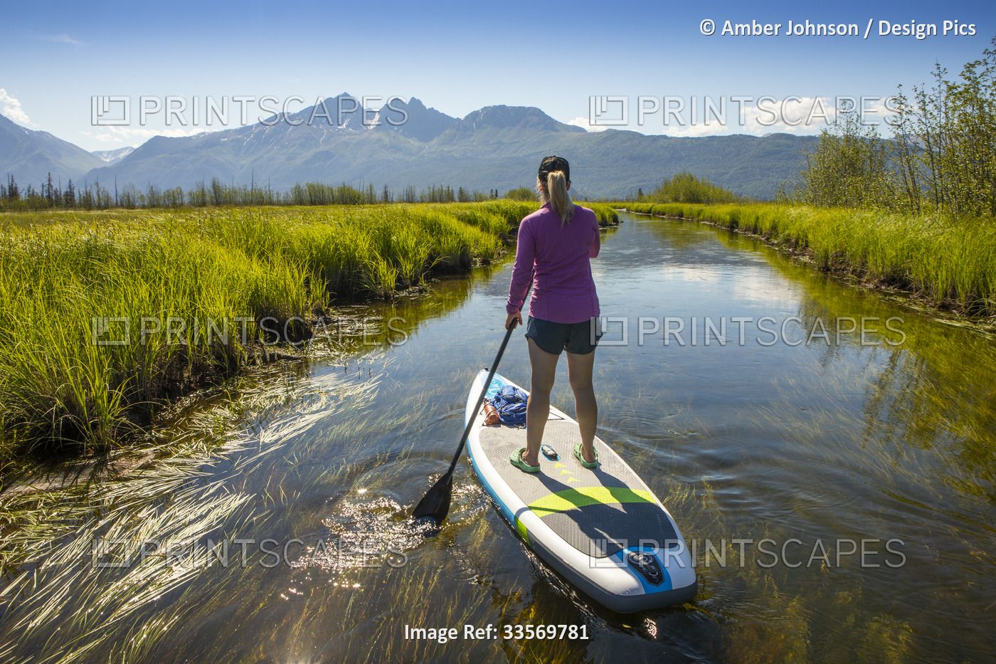 View from behind of a caucasian woman paddle boarding at Rabbit Slough, towards ...
