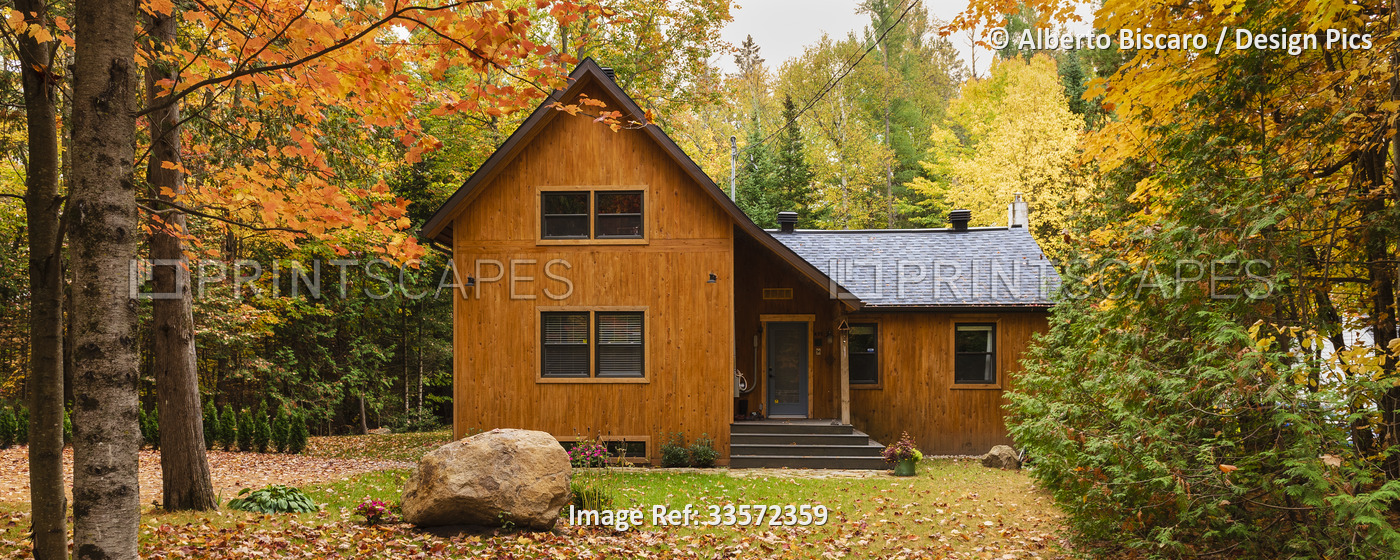 House in the autumn coloured foliage of the Laurentians of Quebec; Quebec, ...