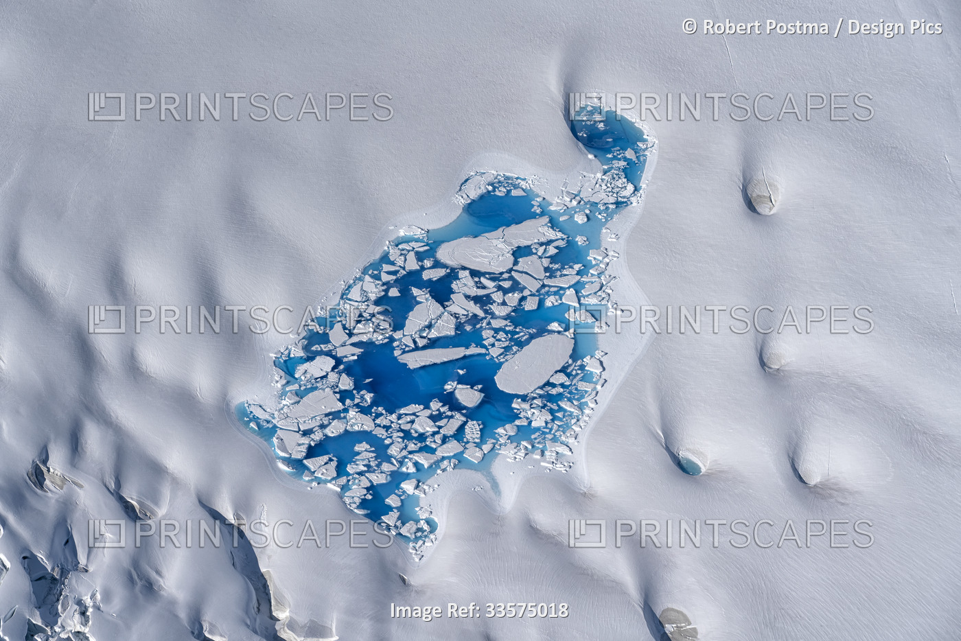 Aerial view of the snow-covered ice mass with a glacial lake in the stunning ...