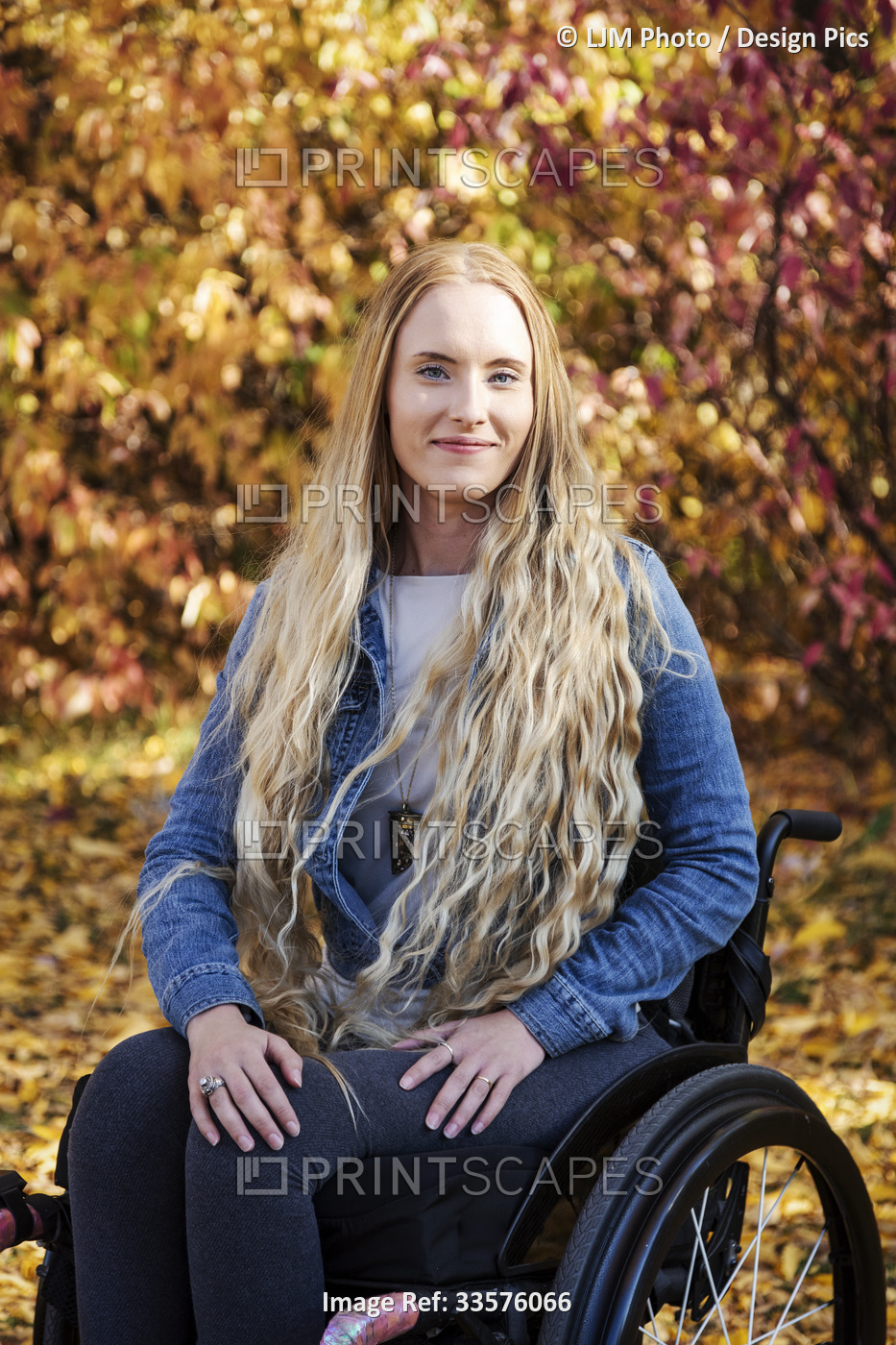 A young paraplegic woman in her wheelchair in a park on a beautiful fall day; ...
