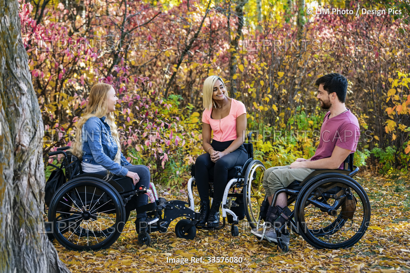 Group of three young paraplegics in their wheelchairs visiting together in a ...