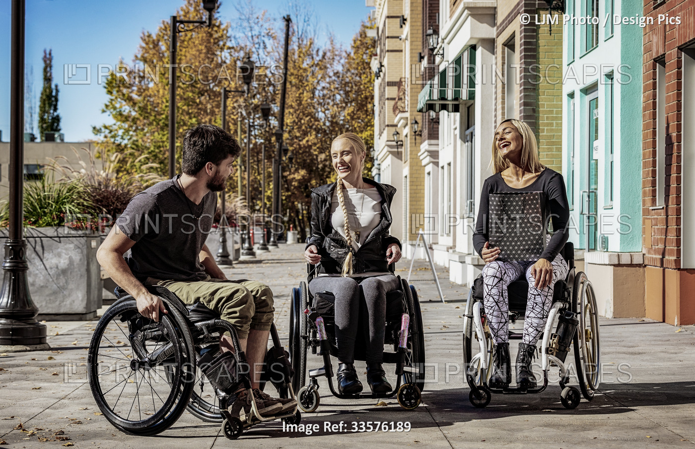 Young paraplegics in their wheelchairs visiting together on a walkway on a ...