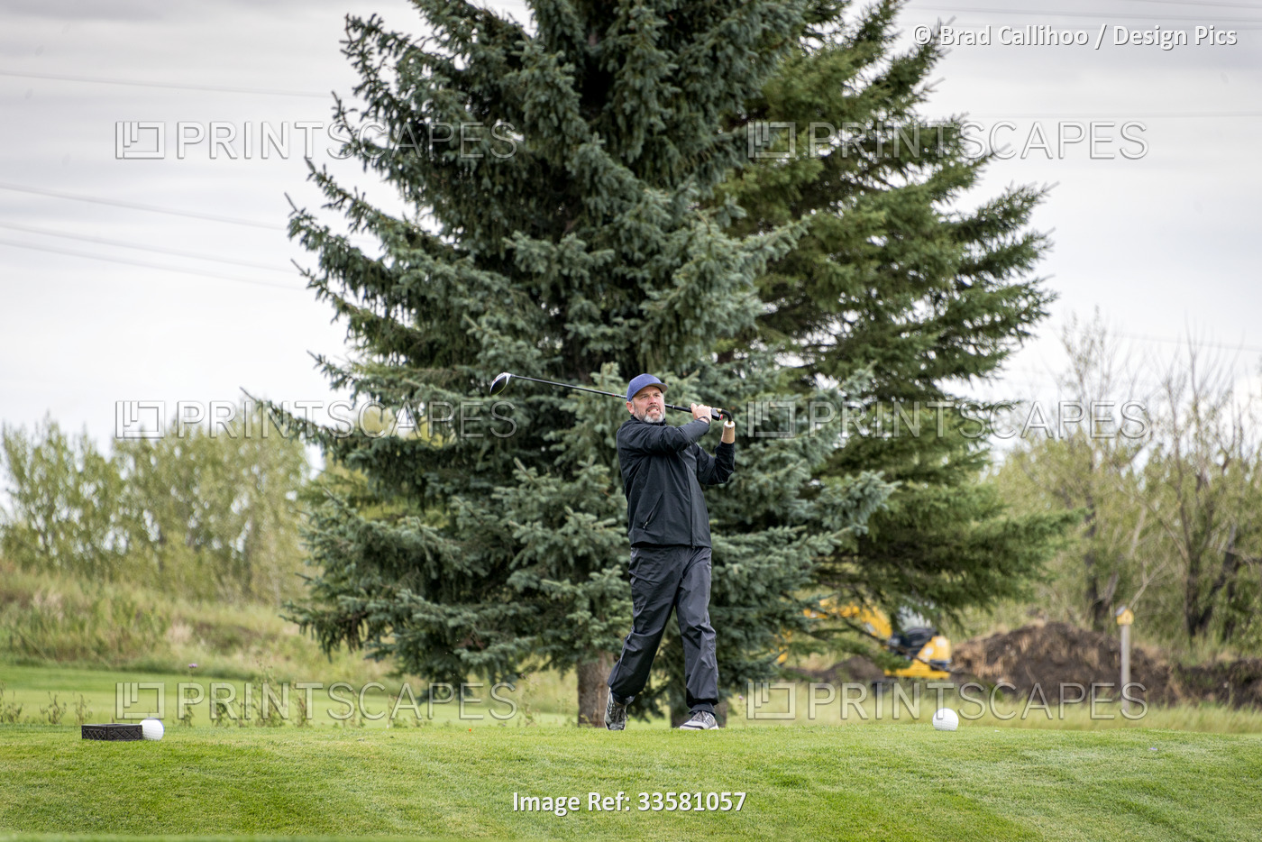 Amputee with one arm prosthesis taking a swing on the golf course; Okotoks, ...