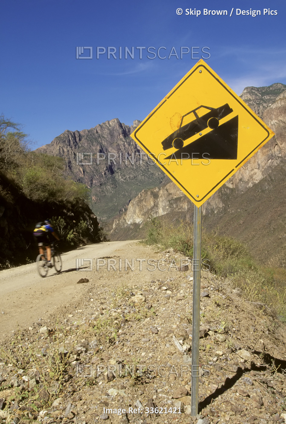 A biker heads downhill past a steep slope sign.; Batopillas Canyon, Sierra ...