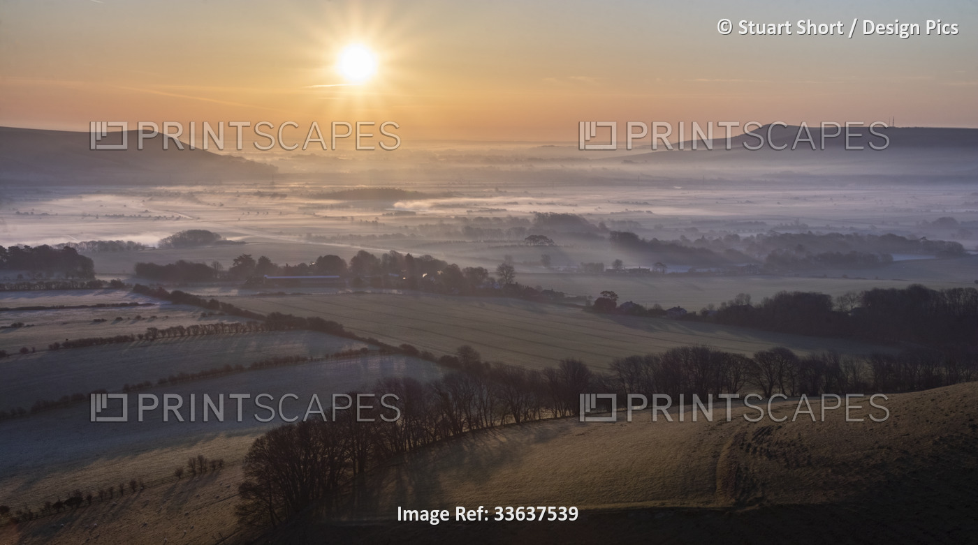 The sunrise casts long shadows over a morning mist inversion lying over the ...