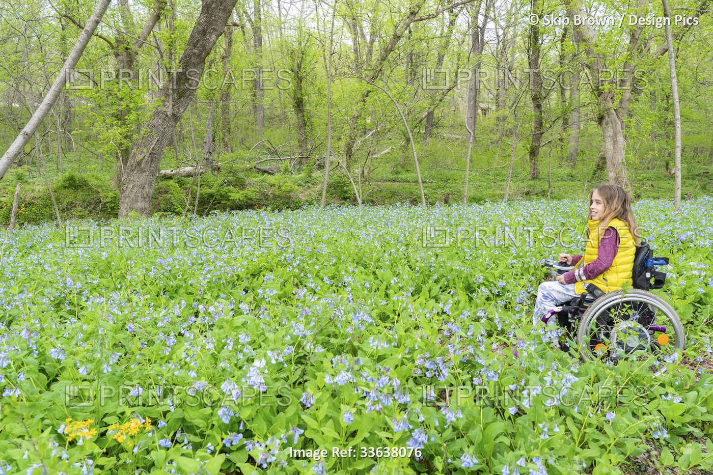 Girl in a wheelchair sits among blossoming wildflowers by the Potomac River; ...