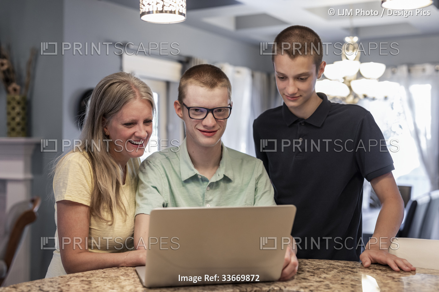 Young man uses a laptop computer at home with support from his mother and ...