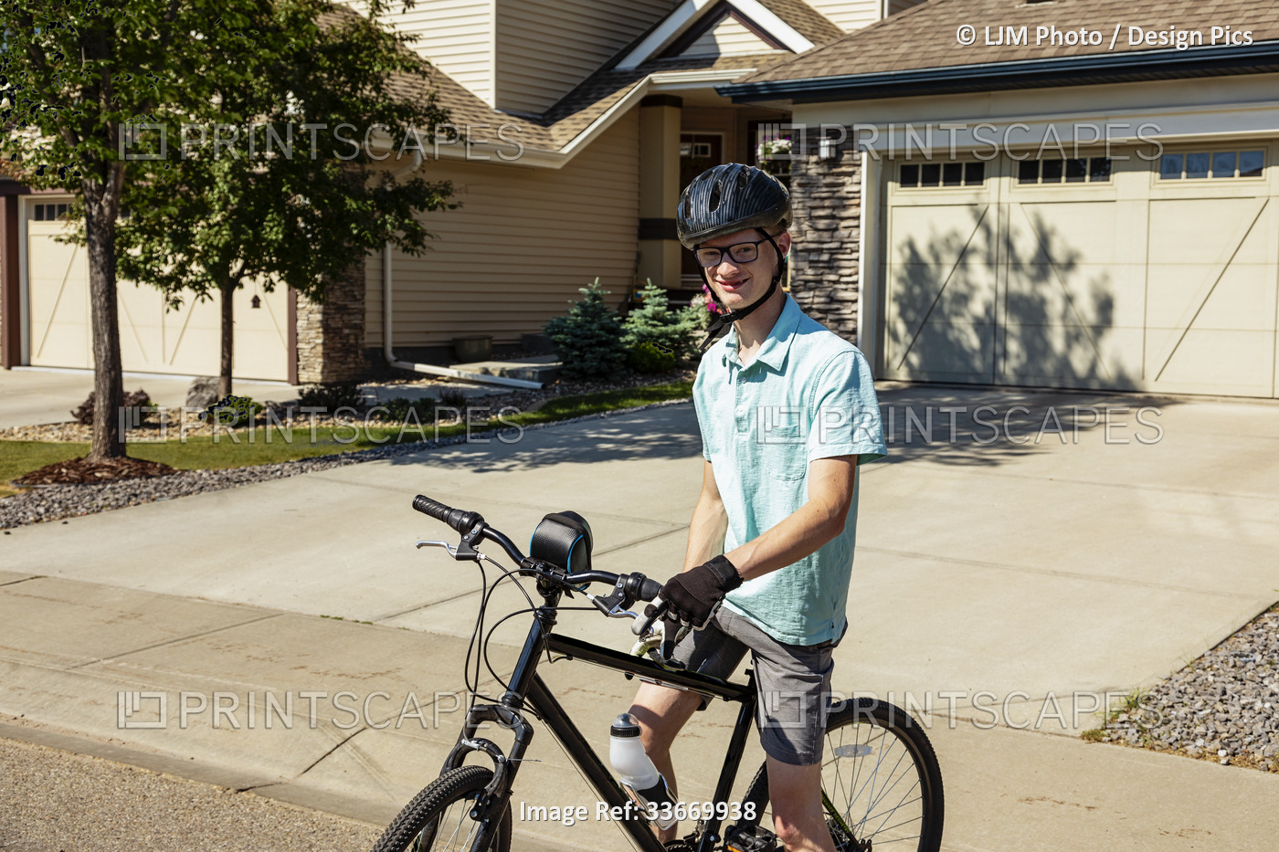 Young man posing on his bicycle on a residential street; Edmonton, Alberta, ...