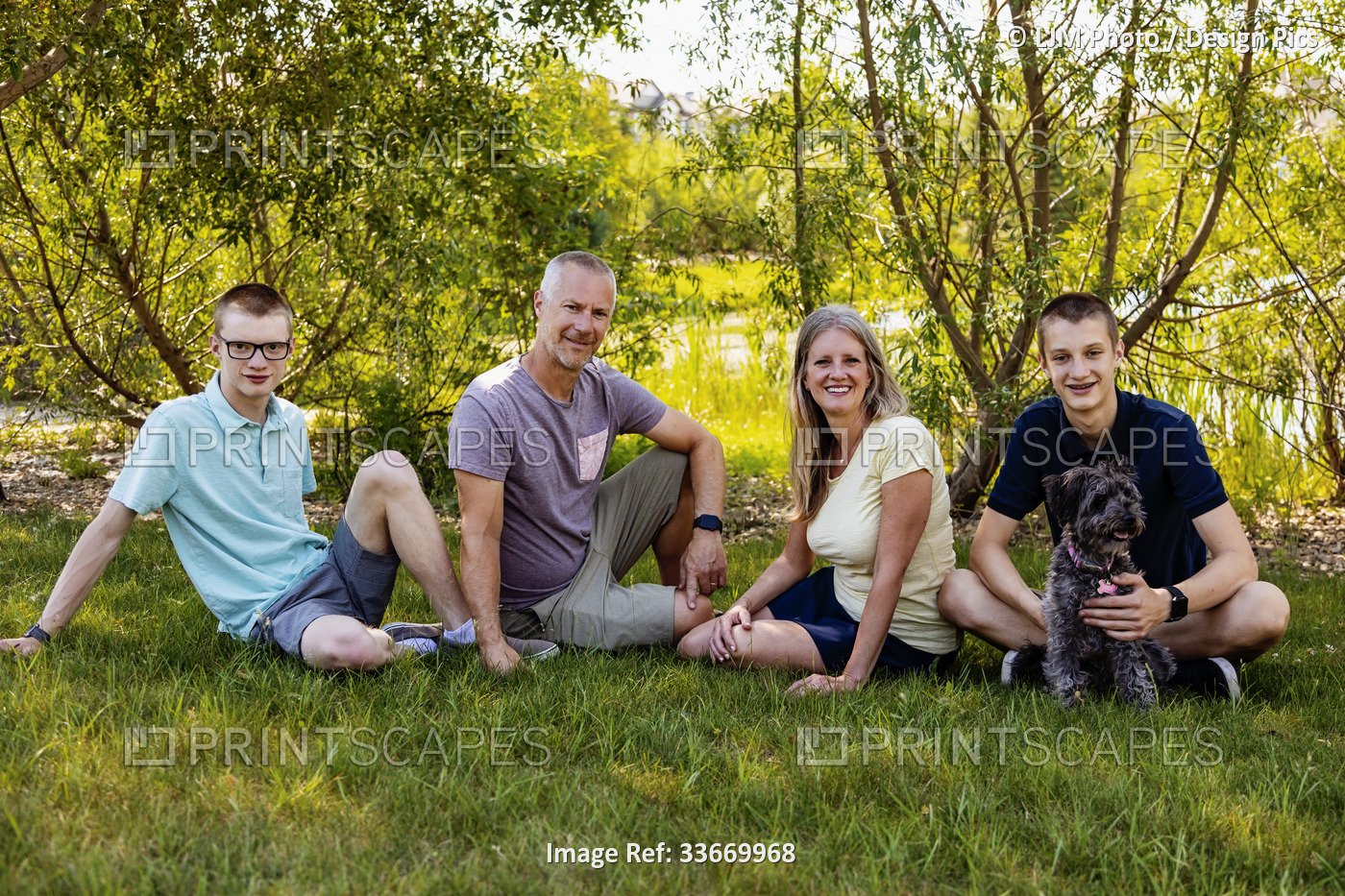 Outdoor family portrait in a park with two teenage sons and a dog; Edmonton, ...