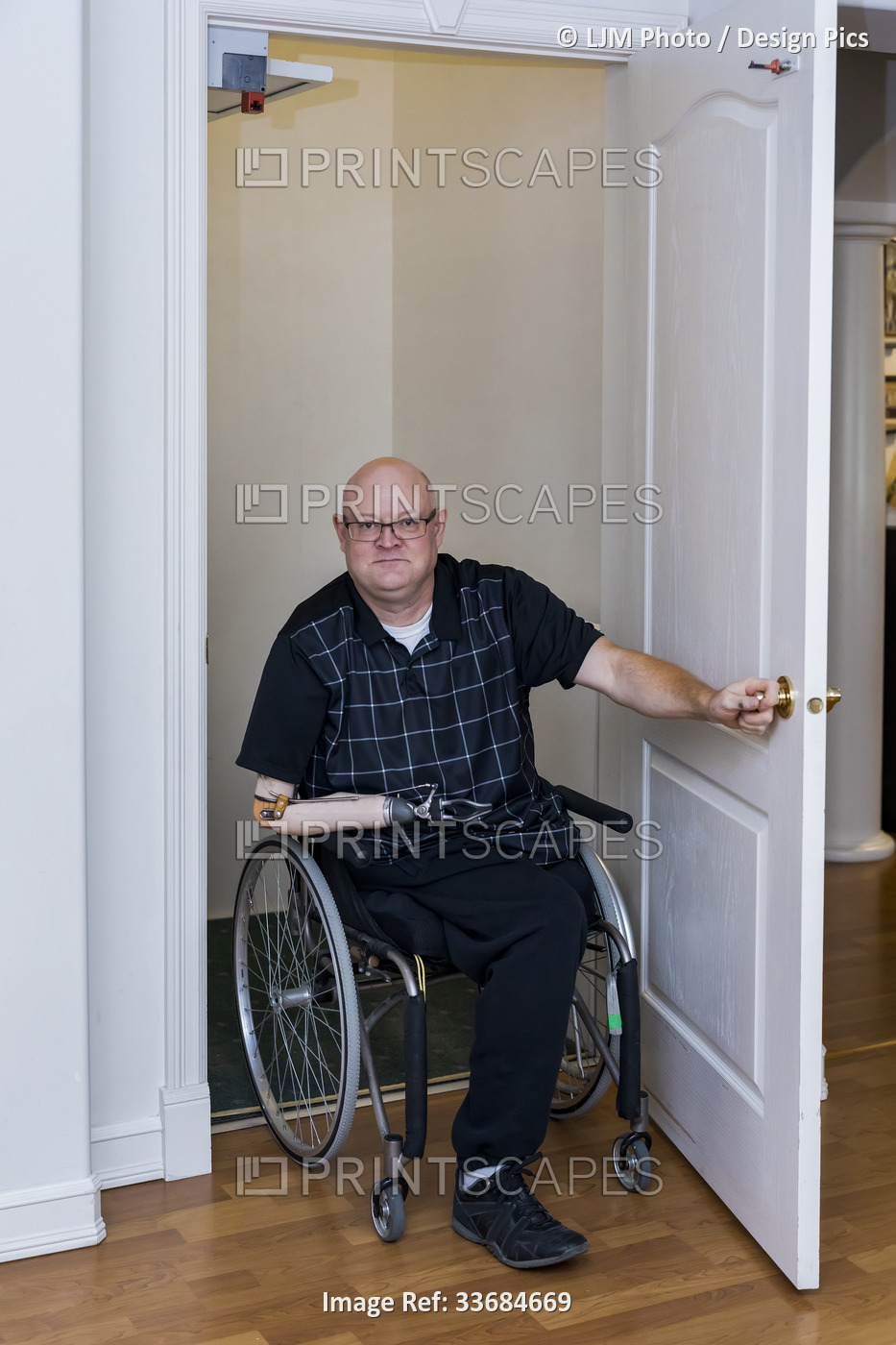Man with double limb amputations entering home elevator; St. Albert, Alberta, ...