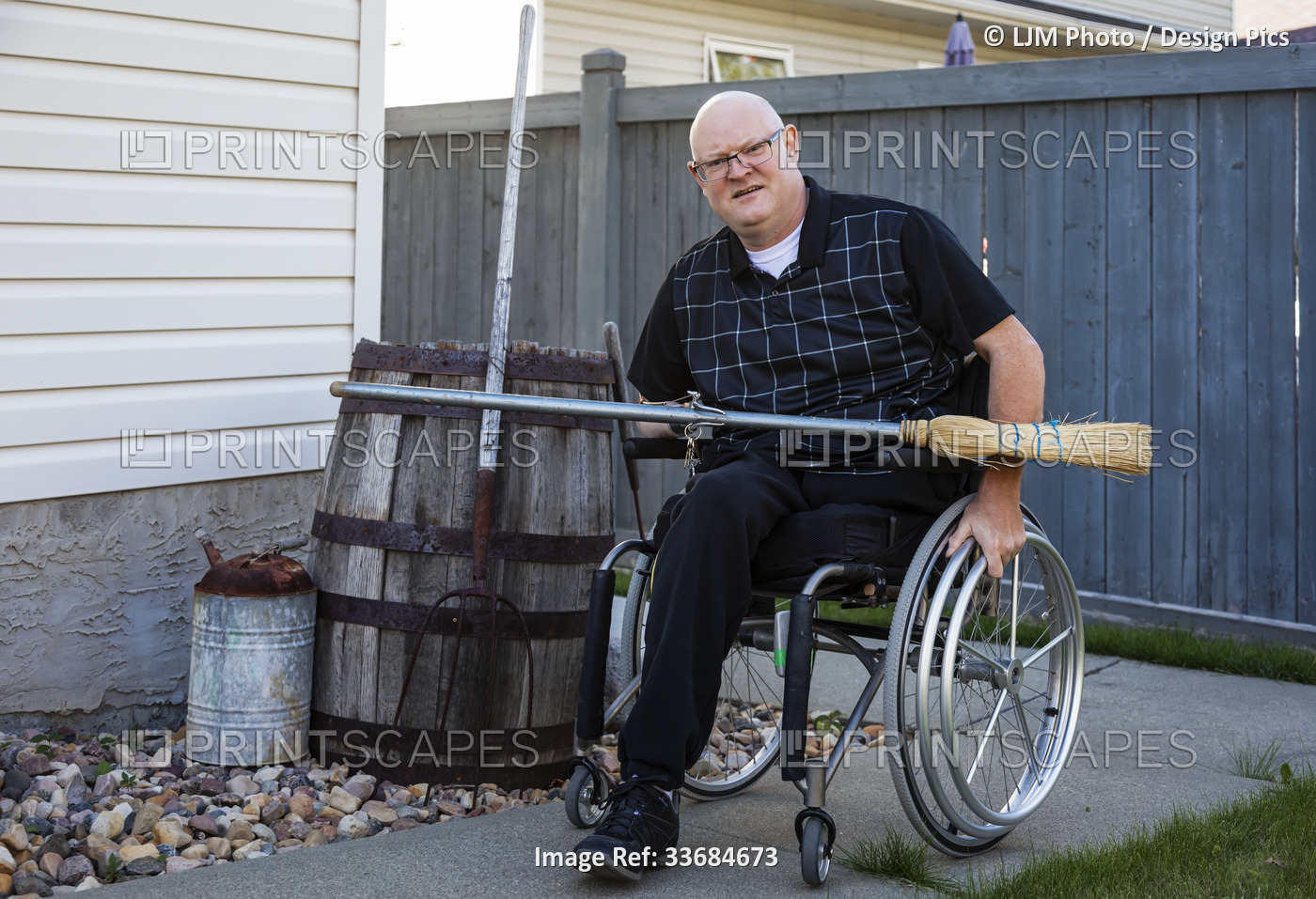 Man with double limb amputations doing yard work in his backyard with a broom; ...