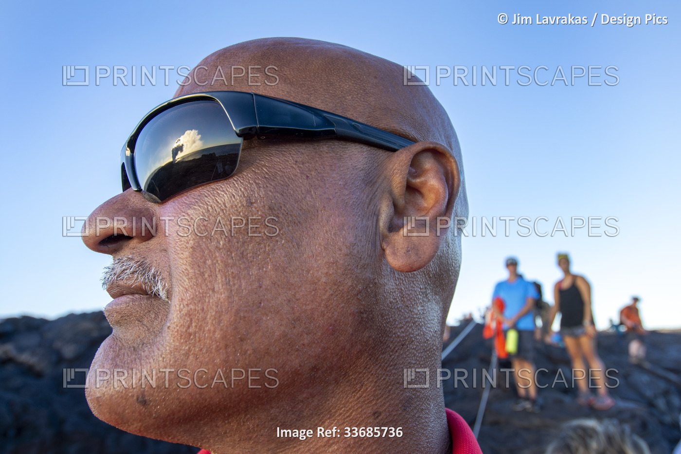 The lava ocean entry on the Big Island of Hawaii is reflected in the sunglasses ...