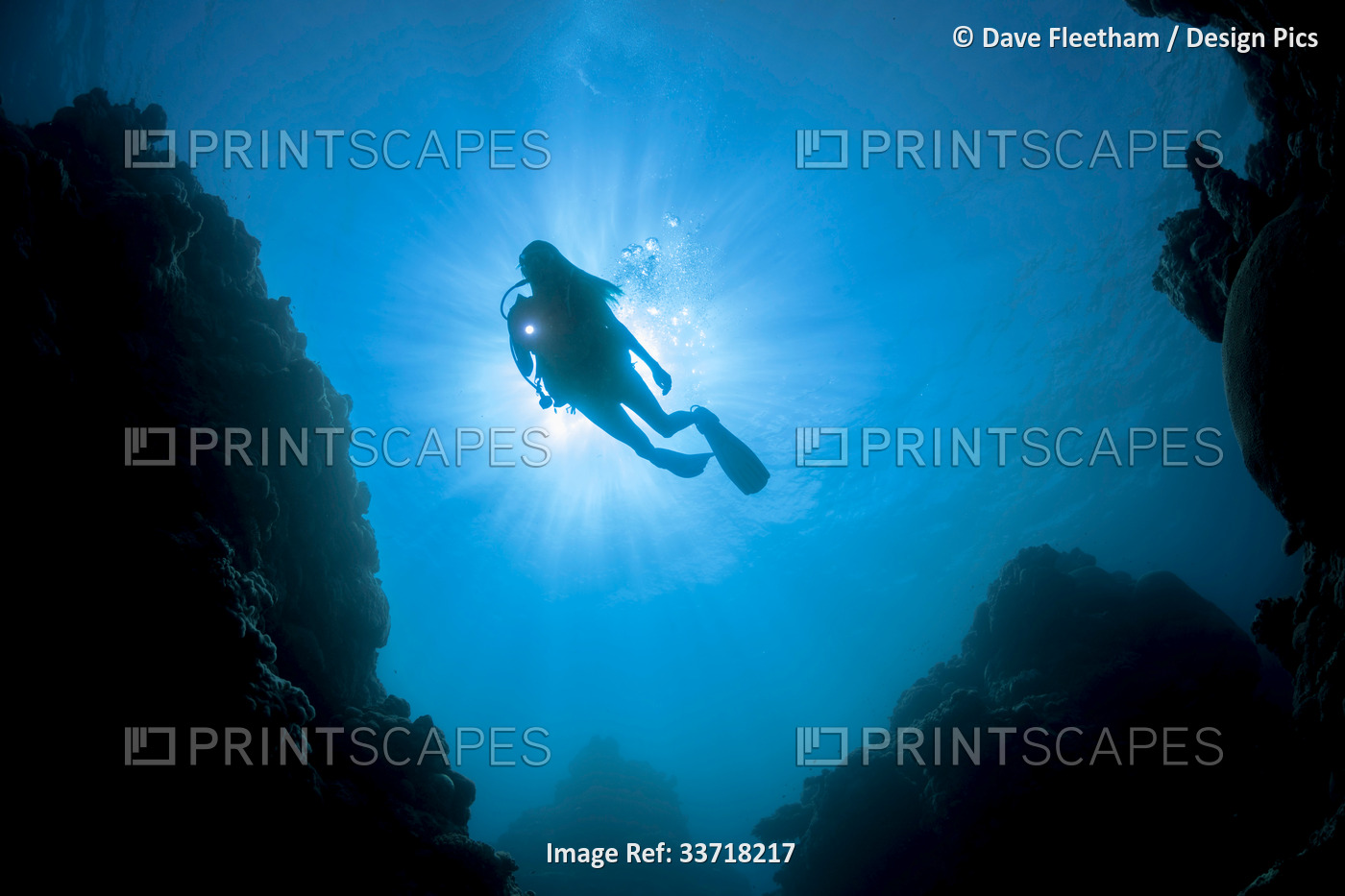Silhouette of diver in front of sunburst at Yap Cavern’s off the very south end ...
