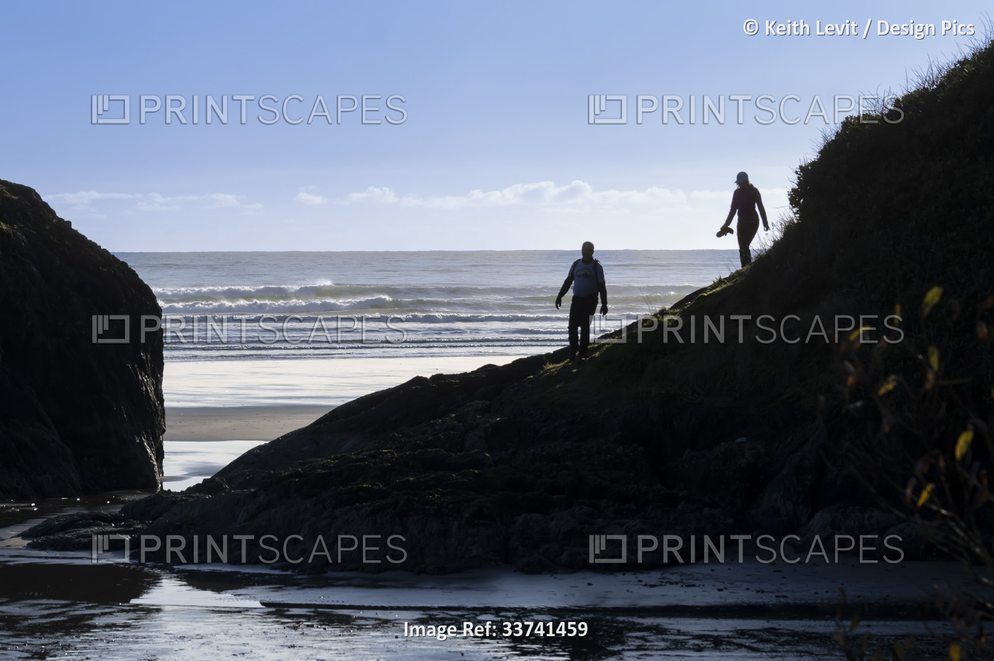 Two people walking on the rugged coastline and exploring the coast of Pacific ...