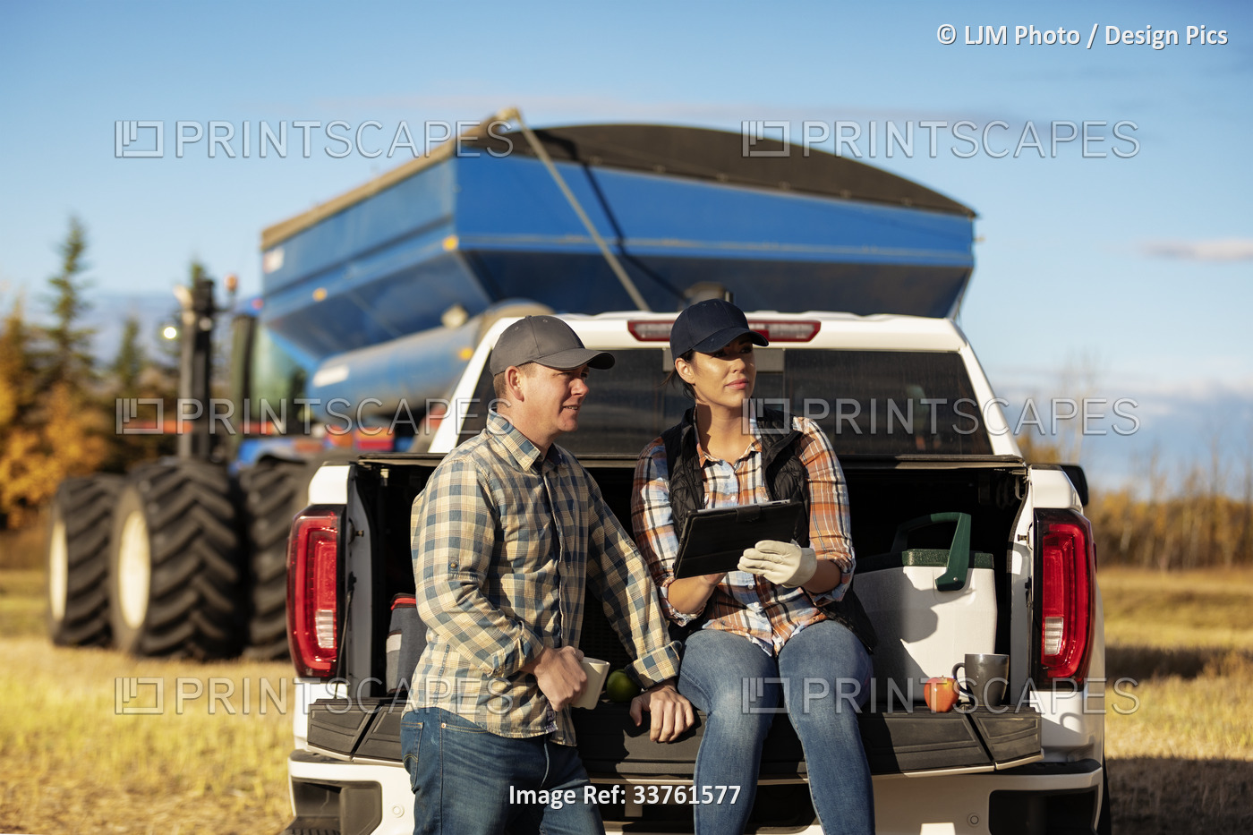 Husband and wife having a coffee while leaning on the tailgate of their ...
