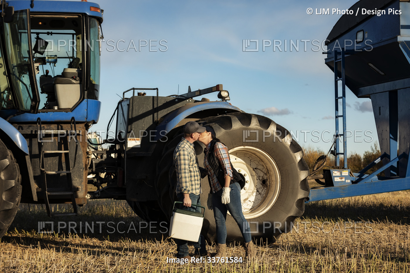 A wife brings her husband lunch at the cab of a tractor and gives him a kiss ...