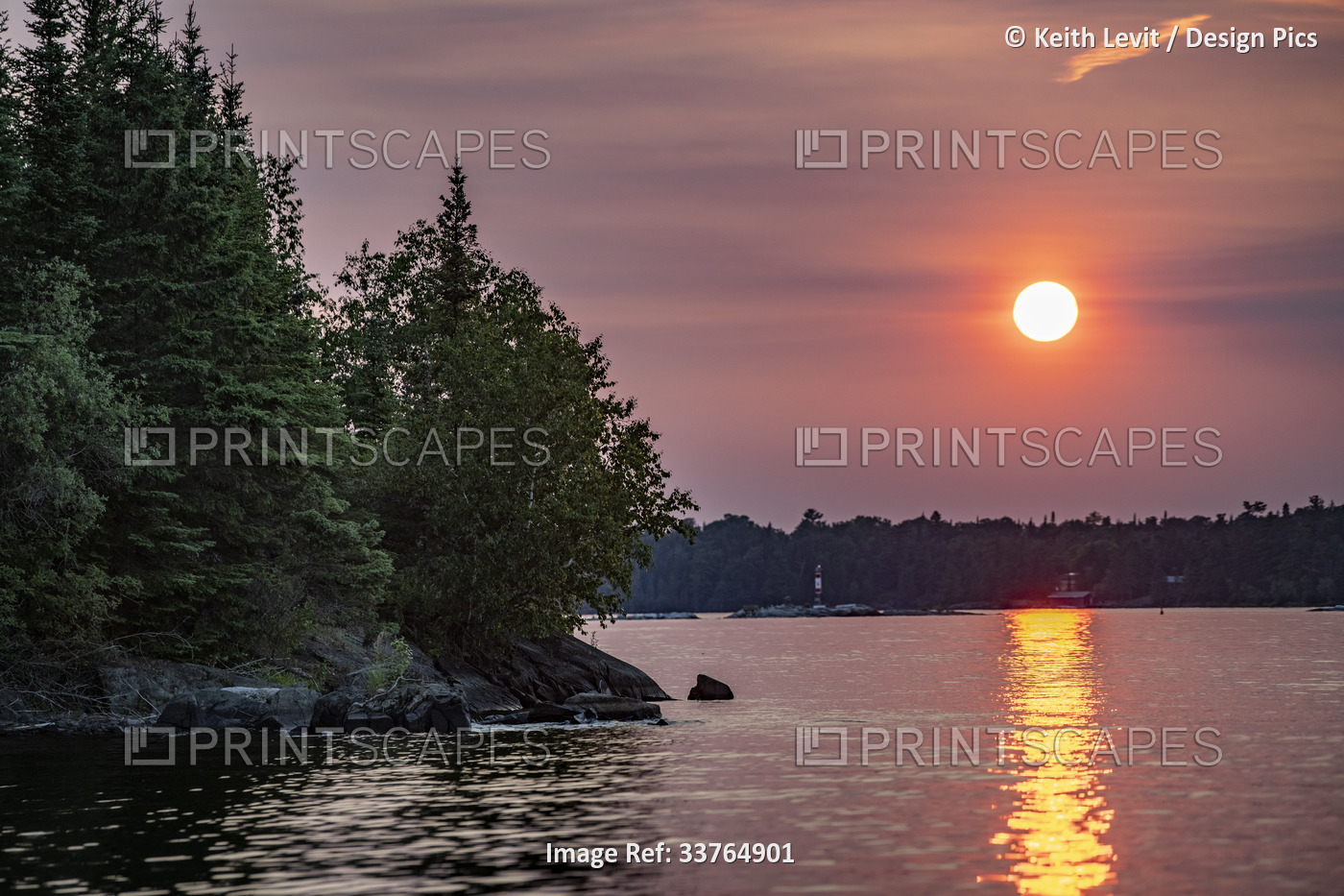Blazing sun reflected on water along a lake and shoreline at sunset, Lake of ...