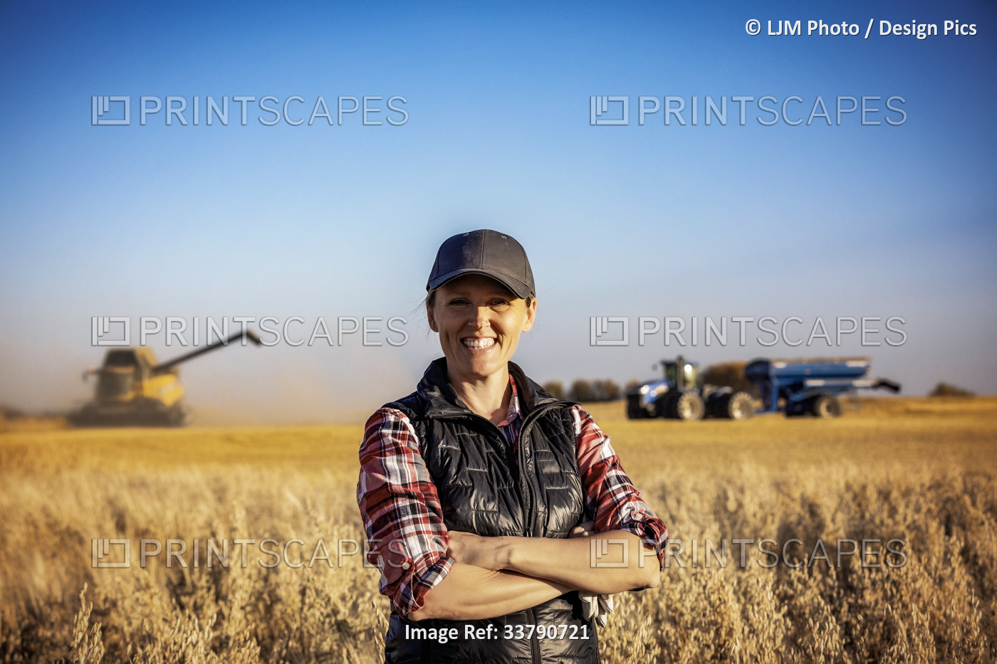 Portrait of a mature farm woman standing in a grain field, posing and smiling ...