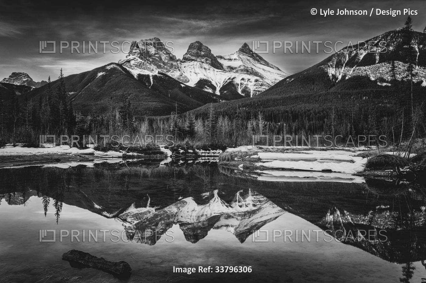 Three Sisters snow-capped mountain peaks reflected in a mirror image in a lake ...