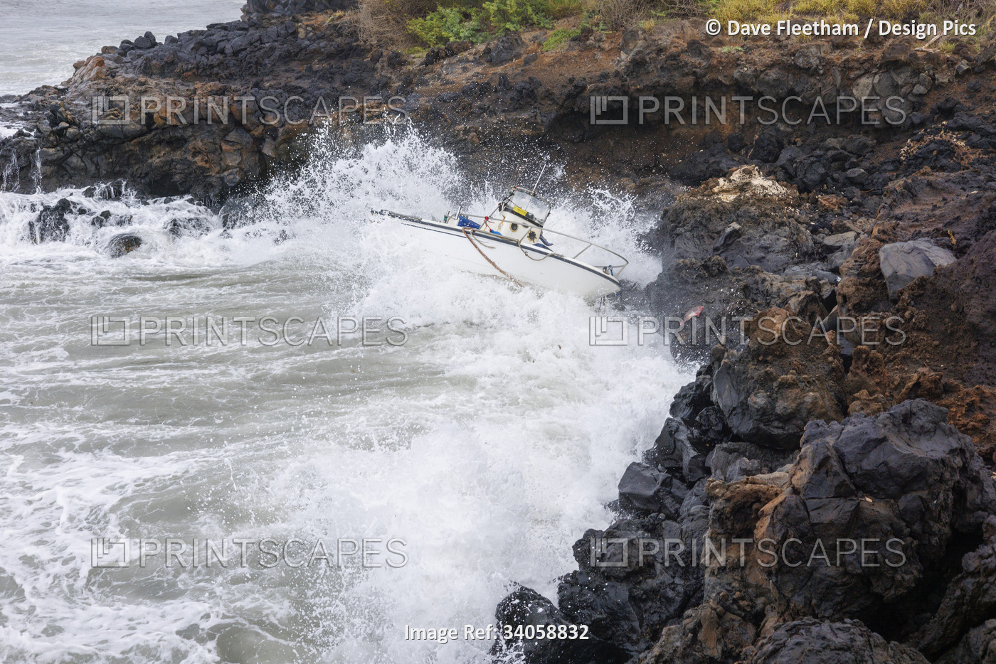 Boat crashing on the rugged seashore after a strong storm in Maui, Hawaii, USA; ...