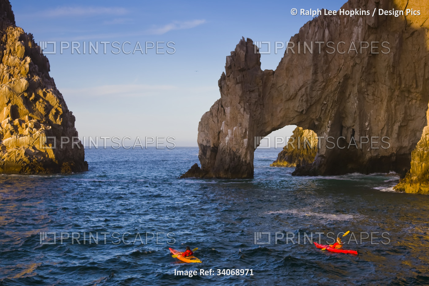 Kayakers at the Land's End Arch rock formations at sunrise.