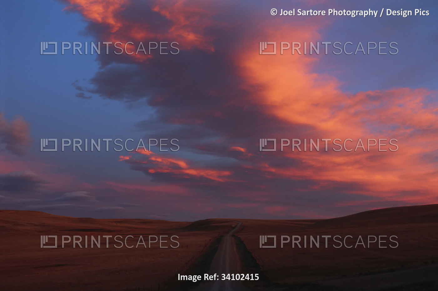 Dramatic glowing pink clouds over vast landscape at sunset; Choteau, Montana, ...