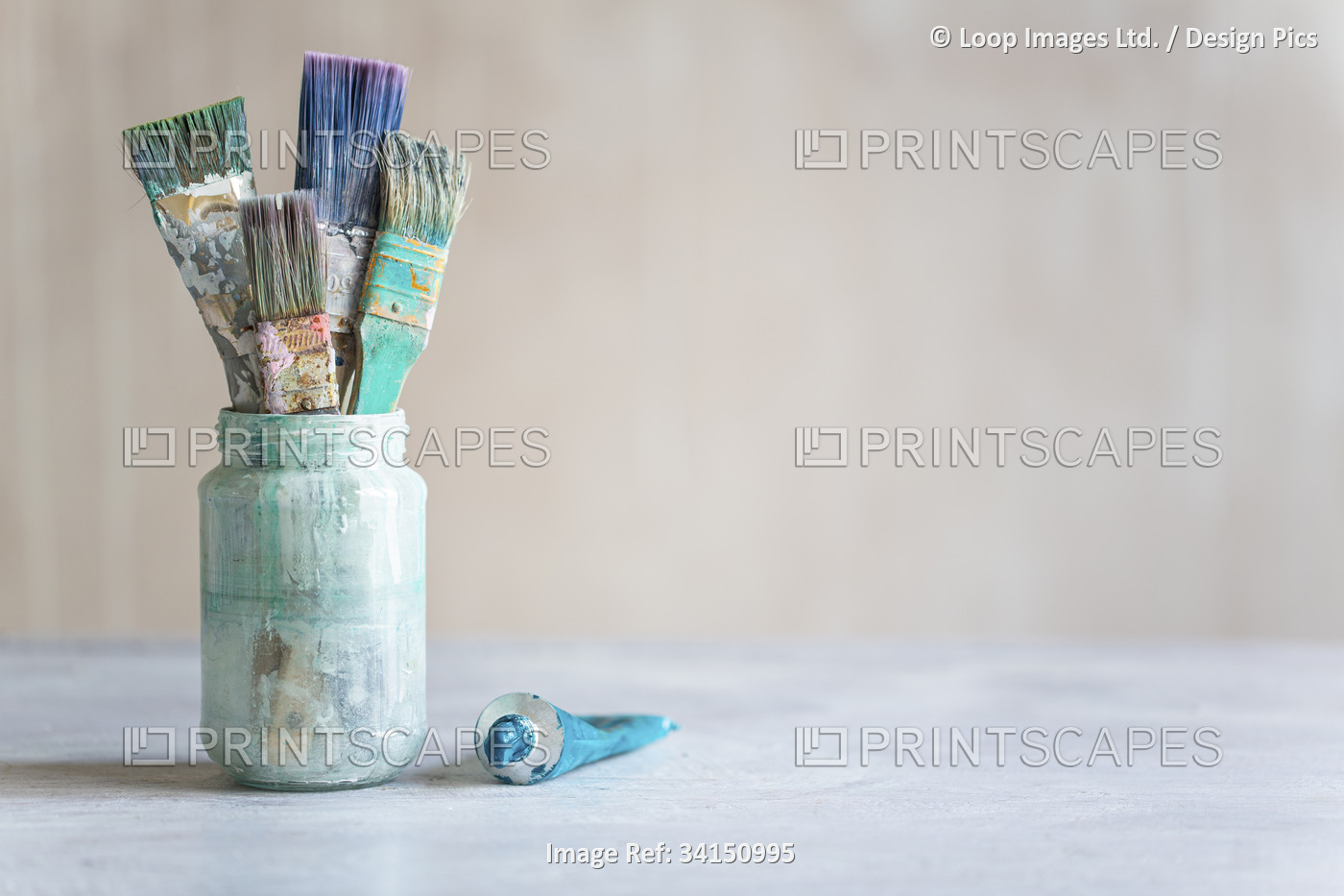 Pot of old paint brushes with tube of paint.