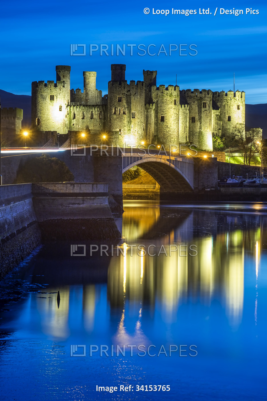 Conwy castle floodlit above the Conwy estuary at night.