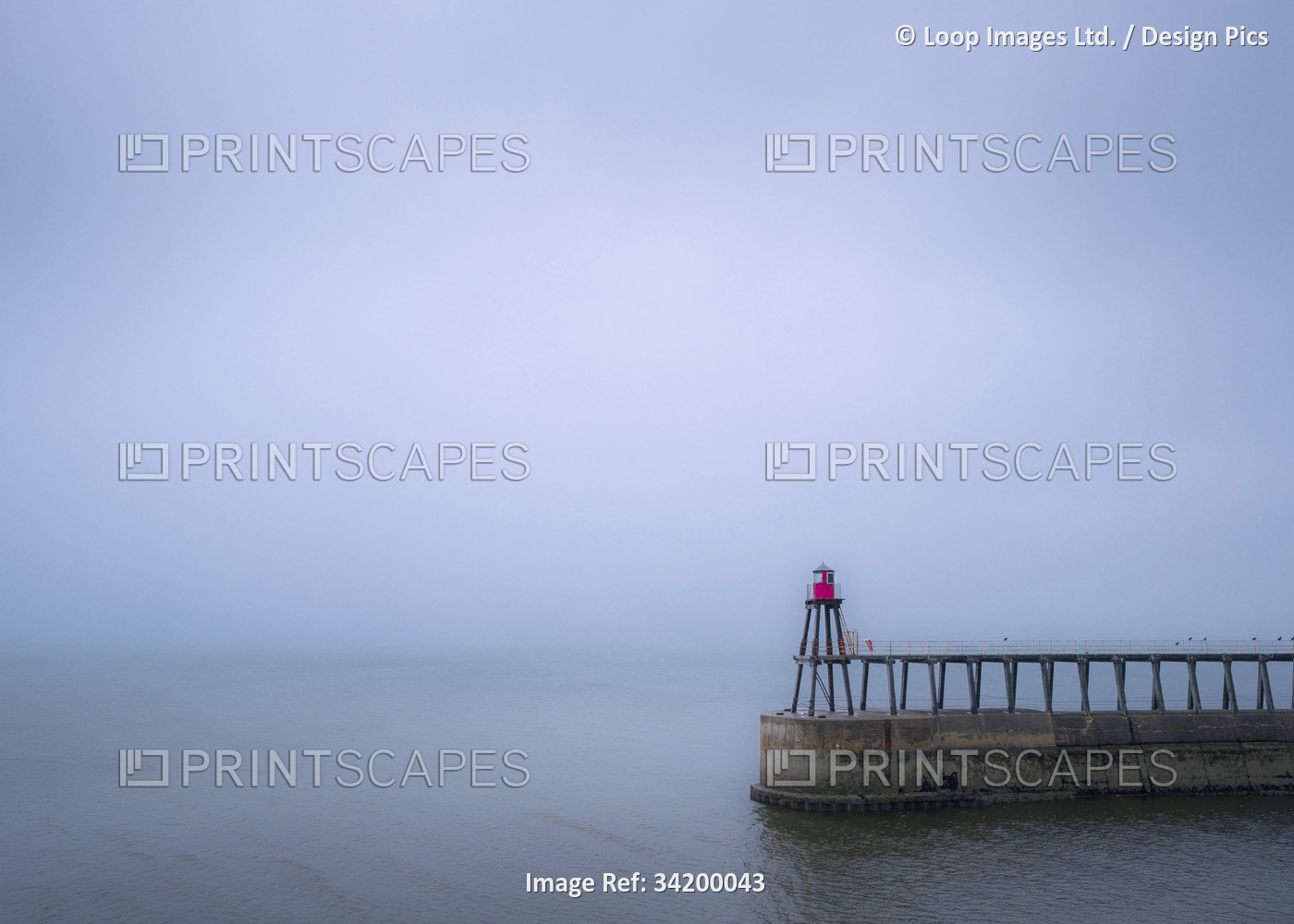 The east pier and lighthouse at Whitby on a misty and rainy day.