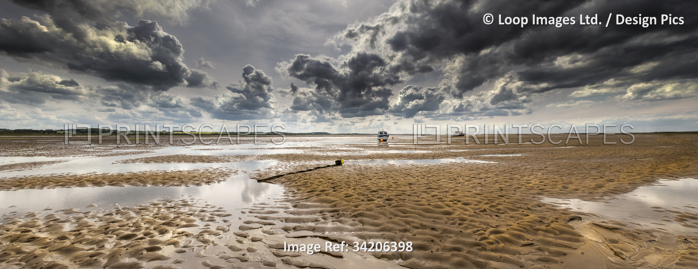 A single boat sitting on the sand at low tide at Morston in Norfolk.