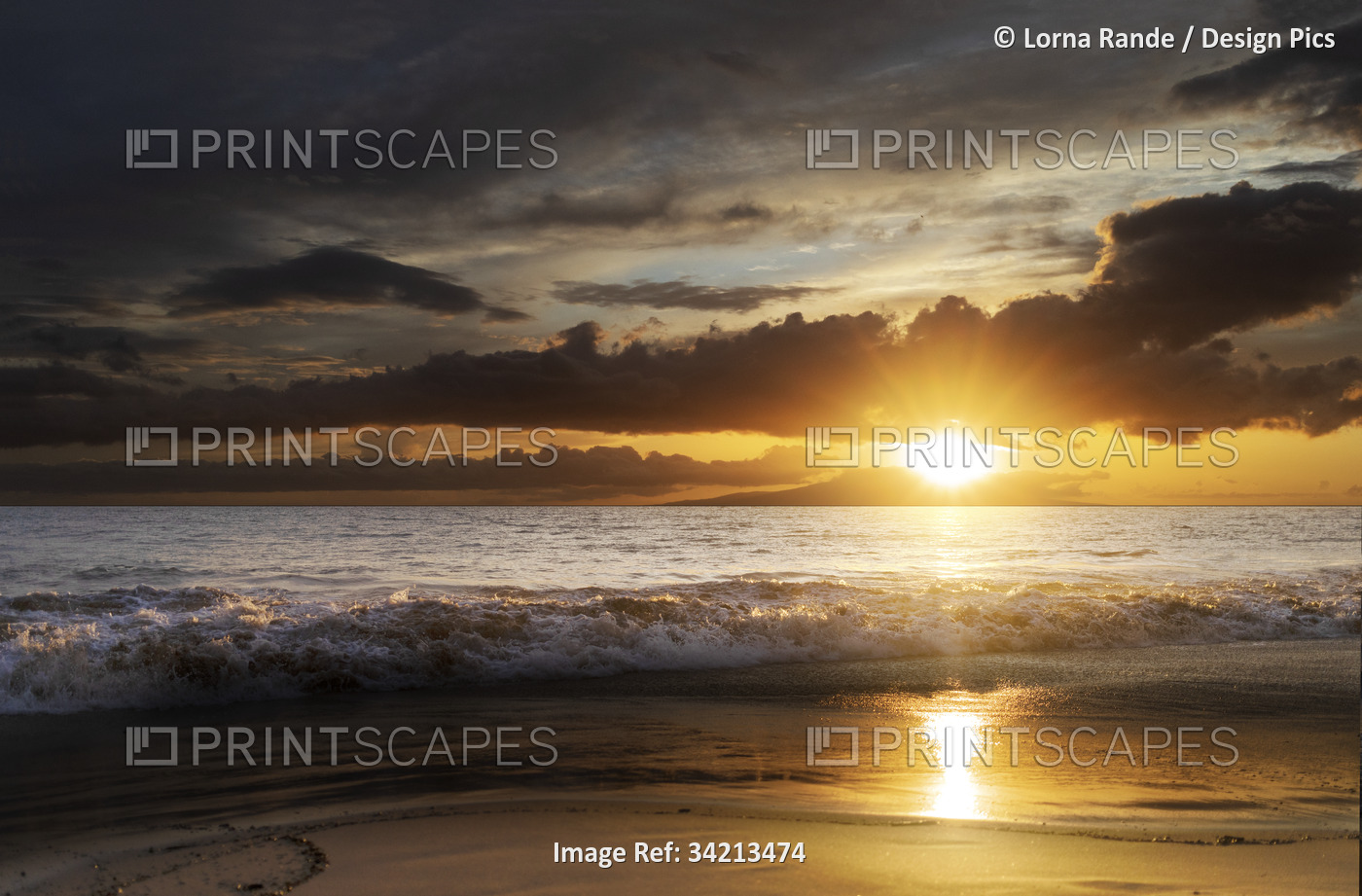 Ocean waves along the shoreline of Kamaole 2 Beach at twilight with a golden ...