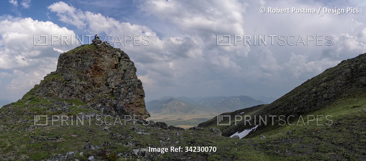 Woman sitting atop Surfbird Mountain along the Dempster Highway, with storm ...