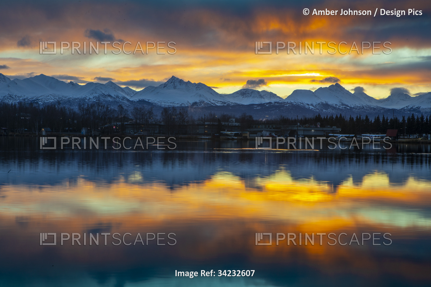 Sunrise on a late autumn, early winter day reflecting on Lake Spenard, with ...