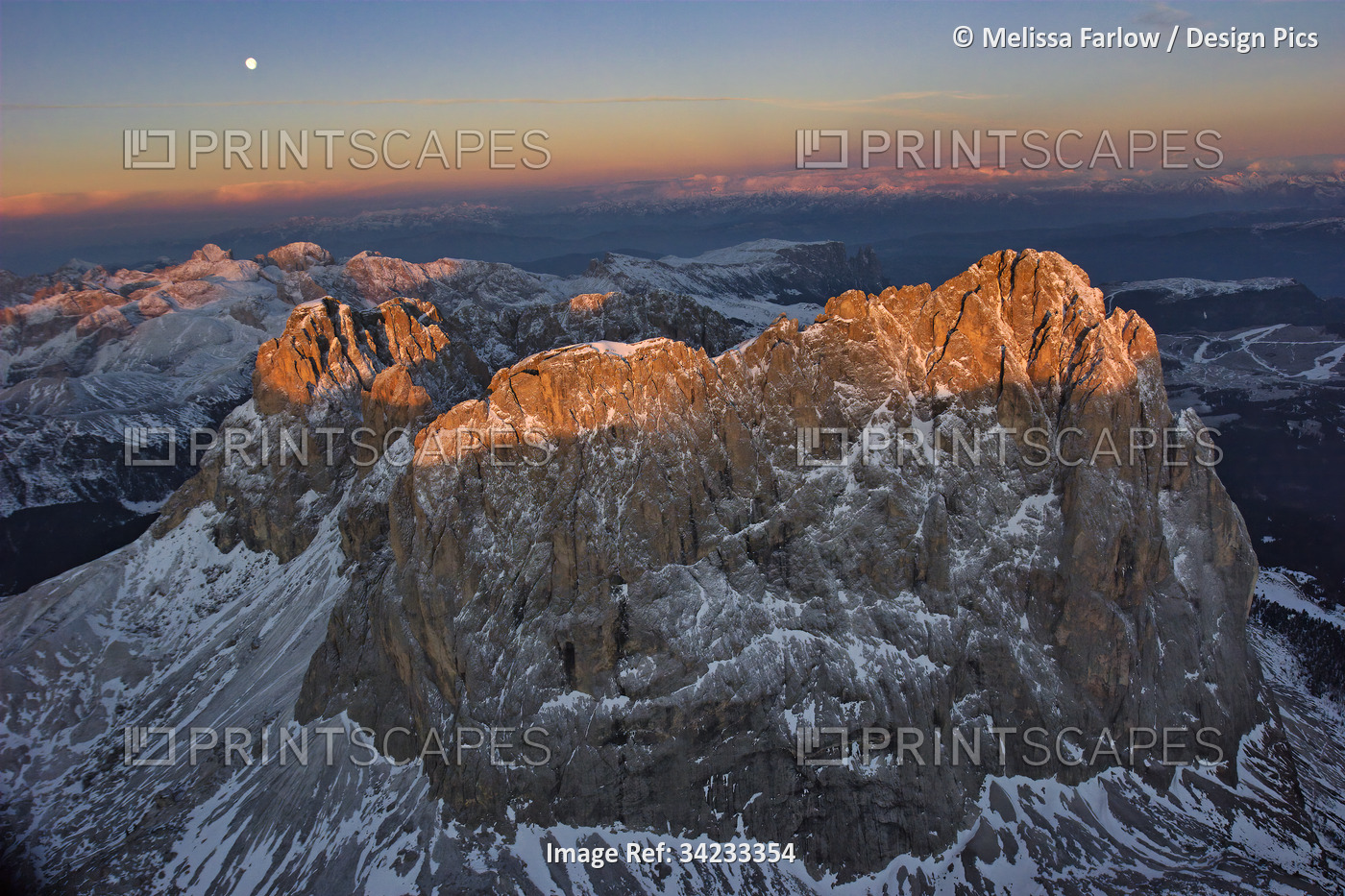 Aerial view of the Dolomite Mountains at sunrise and a visible moon; Ortisei, ...