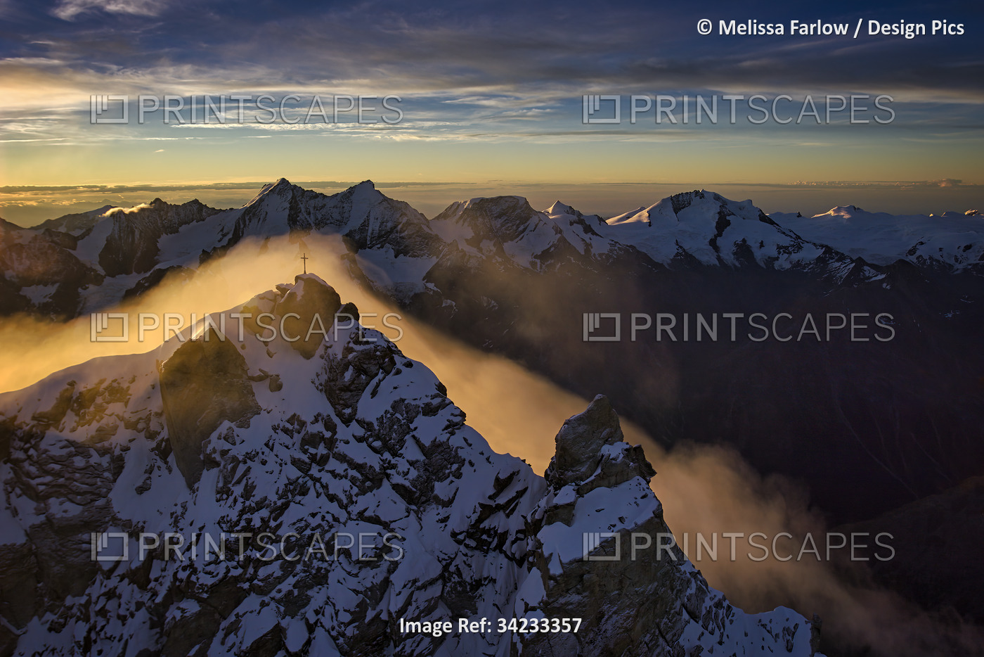 Summit cross surrounded by morning fog in the Alps; Zermatt, Switzerland
