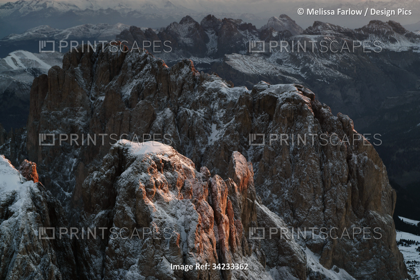Sunlight kisses a snow-dusted peak in the Dolomite Mountains; Ortisei, Italy