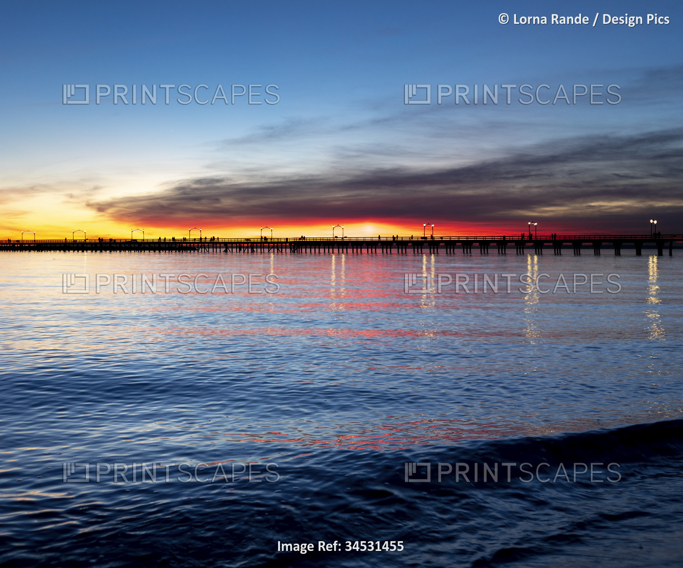 Vibrant sunset colours in the sky over the silhouetted White Rock pier; White ...