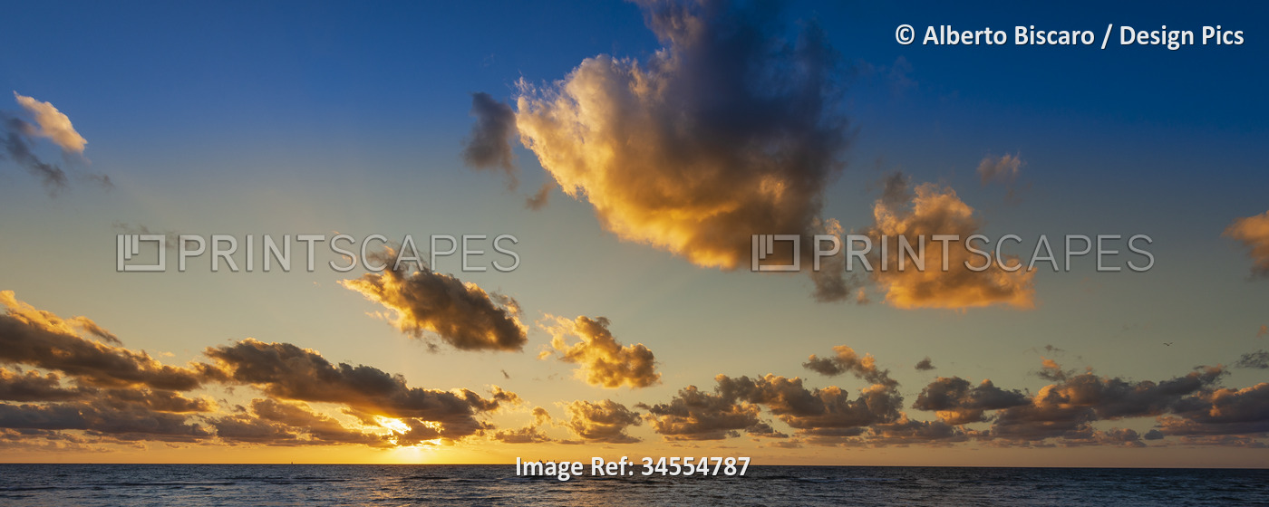 Billowing clouds and golden sunset over Mediterranean sea view; Trapani, ...