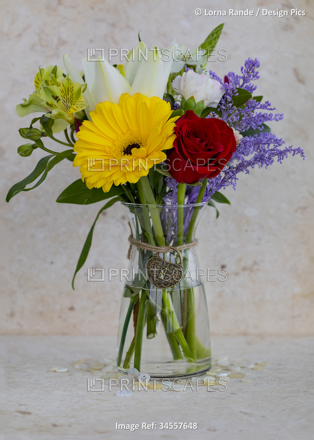 Small, colorful bouquet in a glass vase with a heart-shaped, decorative charm ...