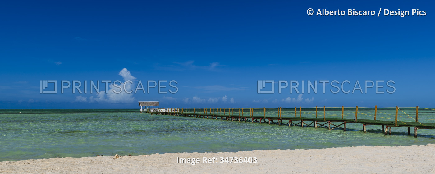 View of a jetty in the turquoise water off the sandy beach of a resort in Cayo ...