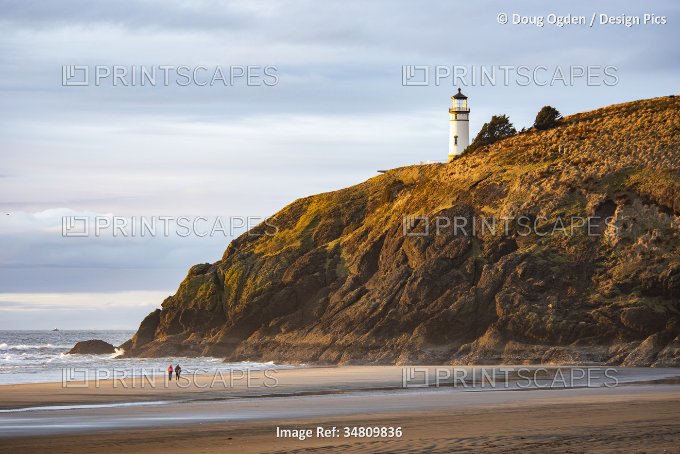 A couple walking on the beach below the North Head Lighthouse at Cape ...